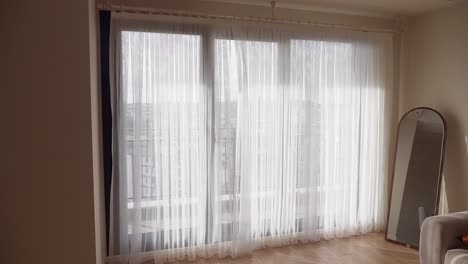 sala de estar luminosa y ventilada con cortinas transparentes y espejo de longitud completa