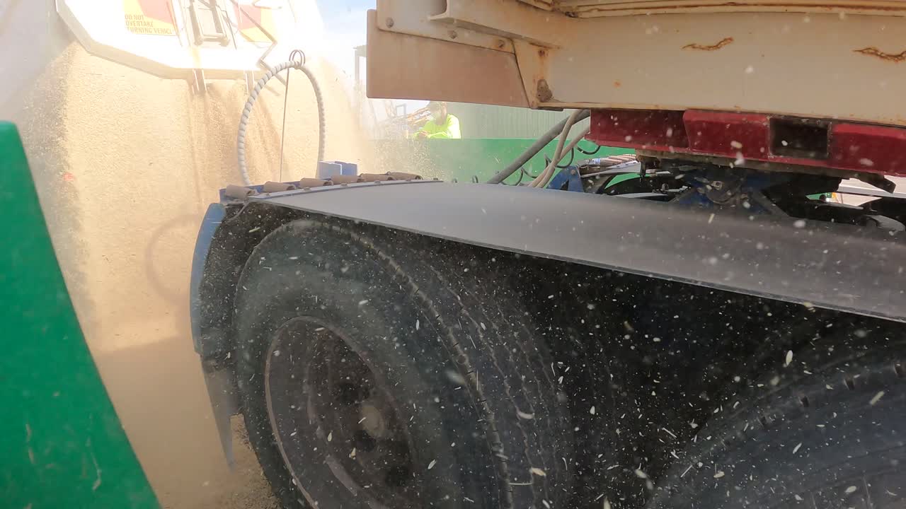 Static shot during harvest season in Western Australia showing a heavy-duty truck unloading golden wheat over a reception grid.