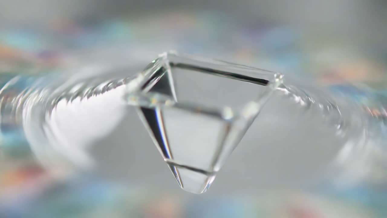 Prism hovering above mirror plane, ripples causing tilting and rotating, facets gleaming for design