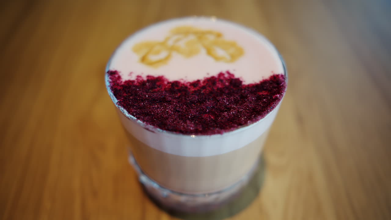 Close up of a latte with pink decoration on top on a wooden table