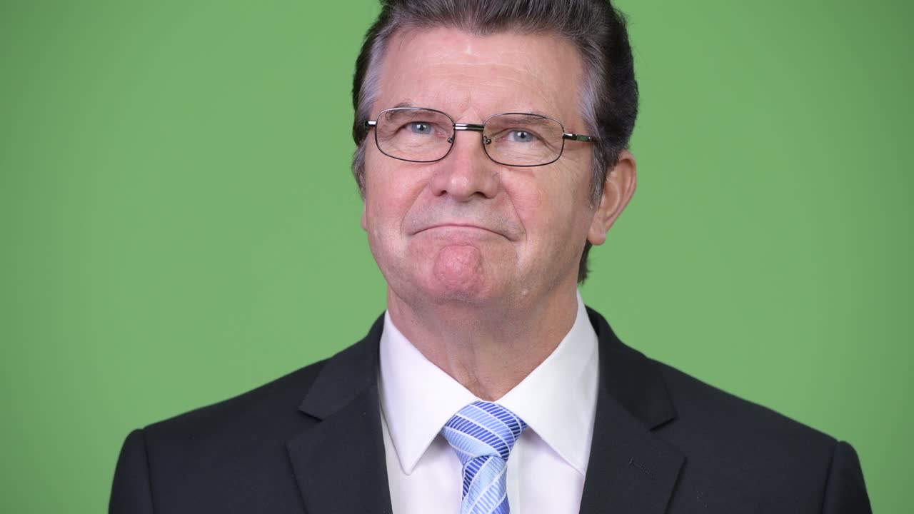 Senior handsome businessman against green background