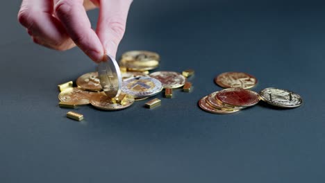 variety of coins symbolizing cryptocurrency along with min gold bars on table, hand shows sides of neo coin.