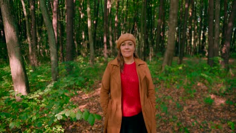 caucasian women with an overcoat and hat walking in the forest trail