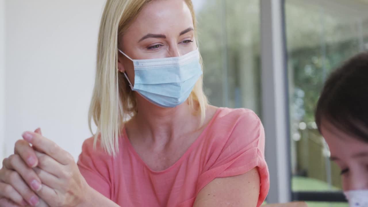 madre e hija usando máscaras faciales desinfectando sus manos en casa