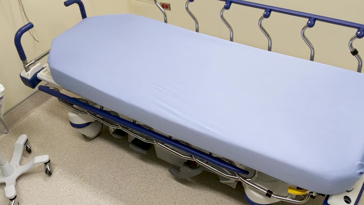 Una cama de hospital vacía esperando a un paciente en una sala de evaluación hospitalaria limpia y bien preparada.