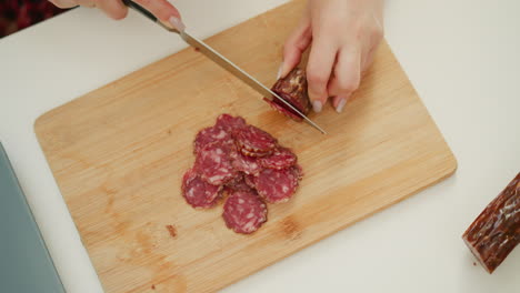 woman slicing sausage on a wooden cutting board