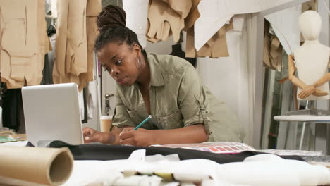 taking notes on the table and using laptop in dressmaking studio