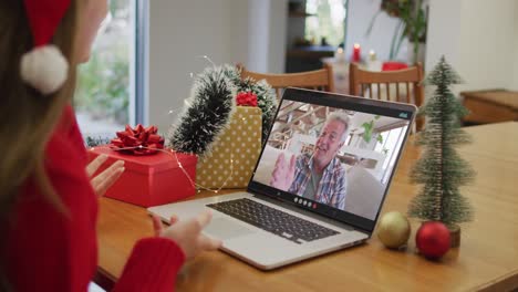 Happy-caucasian-woman-on-video-call-with-grandfather-at-christmas-time