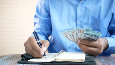 hombre escribiendo en un cuaderno con dinero