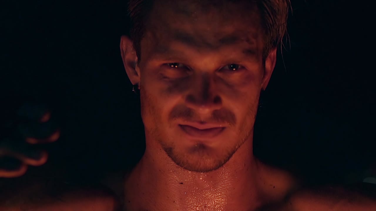 금발 남성이 두 마리의 포를  ⁇ 사슬에 매달고 있다. 남자는 카메라를 쳐다보고 얼굴과 목이  ⁇ 을 흘리고 있다.