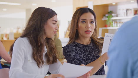 group of business colleagues having informal meeting around table in office coffee shop