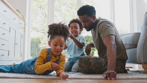 army father in uniform home on leave with children doing jigsaw puzzle together