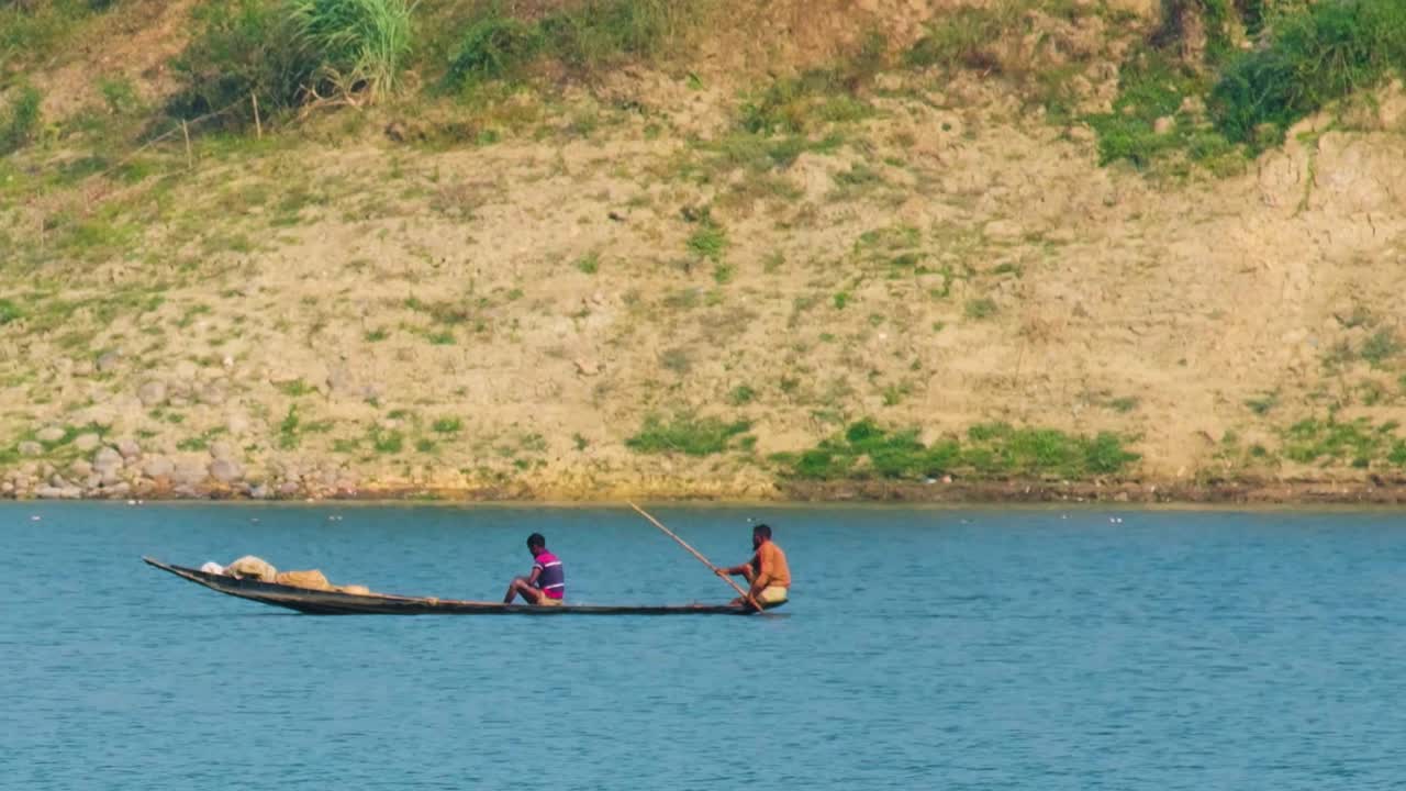 To fiskere fanger fisk med net på en flod i Bangladesh.