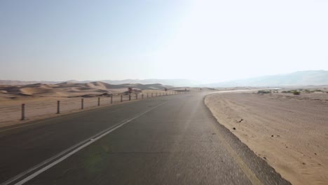 pan right driving through empty barren desert road to reveal incredible abu dhabi sand dunes on sunny day