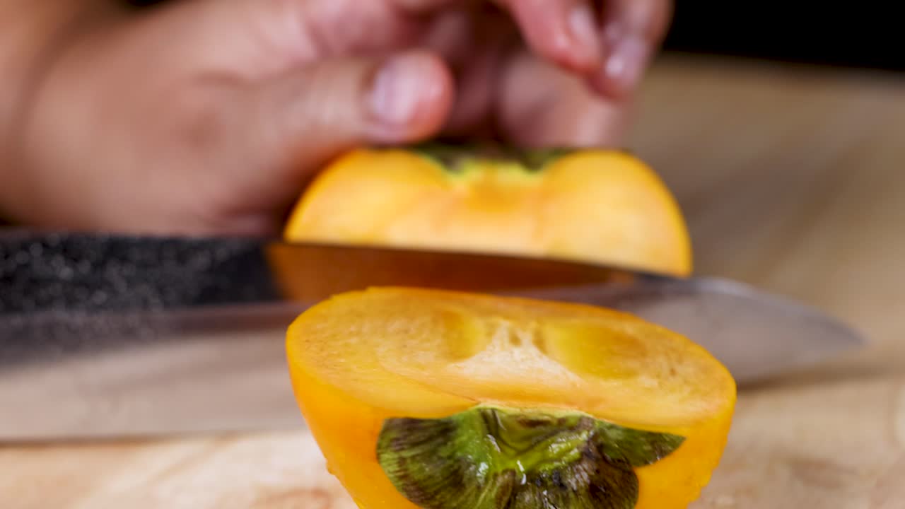 손 이 칼 으로 익은 파시몬 을 자르고 있다