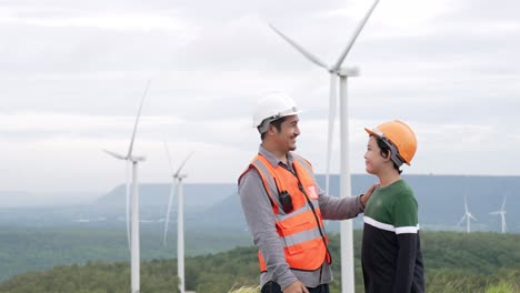 progressive engineer with his son in the wind farm atop of the mountain.