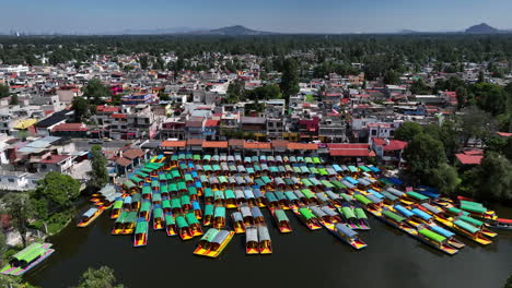 Drone-circling-Trajinera-boats-docked-at-the-Xochimilco-Lake,-in-sunny-Mexico