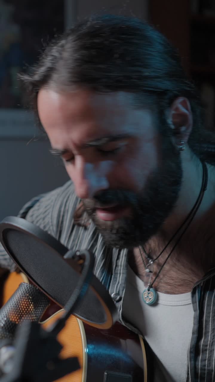 Musician singing and playing acoustic guitar into a microphone