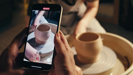 person making pottery on a pottery wheel, filmed on a smartphone