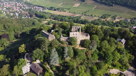 ruins of badenweiler castle atop forested hillside overlooking spa town, aerial