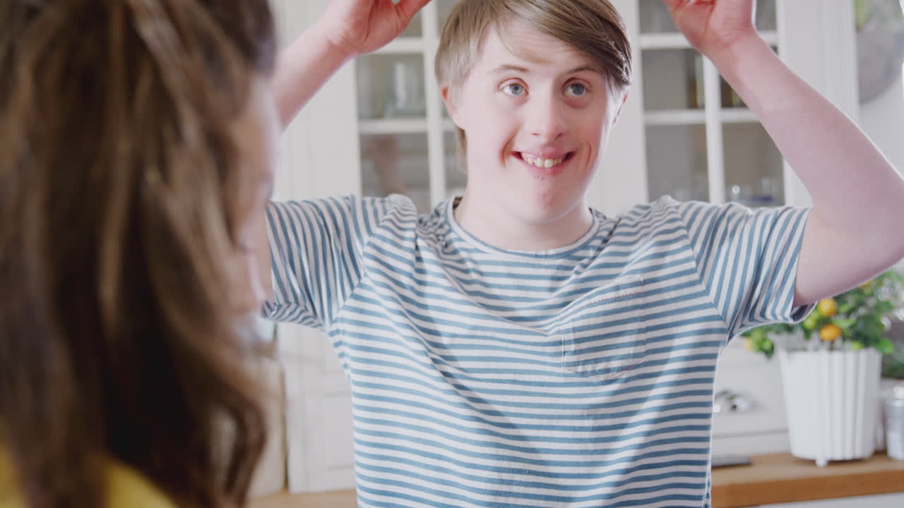 Young Downs Syndrome Couple Making Bunny Ears With Marshmallows As They Decorate Cupcakes At Home