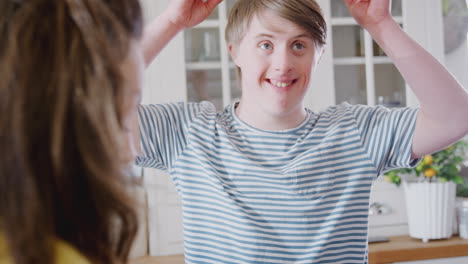 young downs syndrome couple making bunny ears with marshmallows as they decorate cupcakes at home