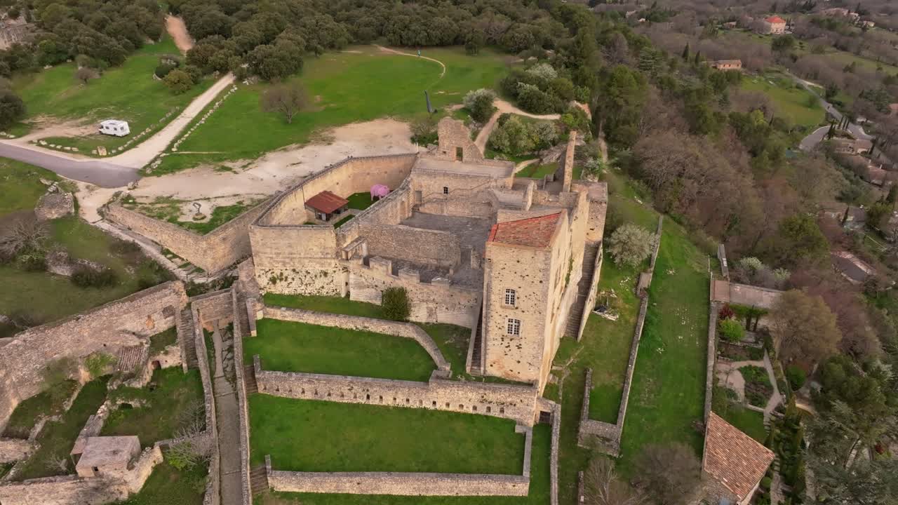 Aerial view of historic Lacoste and its fortress under golden dawn skies