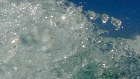 Extreme-low-angle-water-surface-pov-of-motorboat-wake-trail-over-blue-seawater