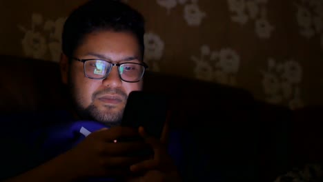 man using phone at night on couch