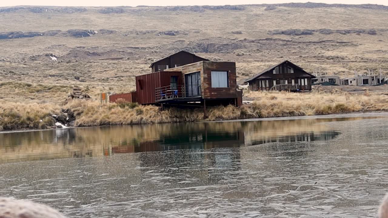 cabaña de madera fría en un lago con un fondo nevado claro