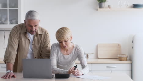 elderly couple budgeting in kitchen