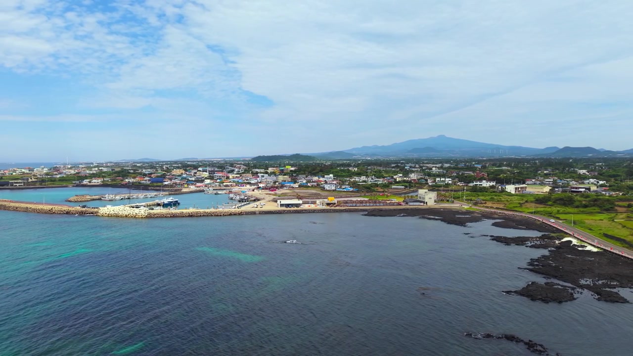 Vista aerea del villaggio costiero di Sinchang-ri presso il Parco Singgyemul, Hangyeong-myeon, Isola di Jeju, con un frangiflutti portuale e il monte Hallasan