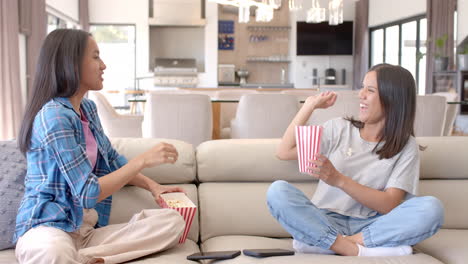 eating popcorn and chatting, two teenage girls hanging out on couch