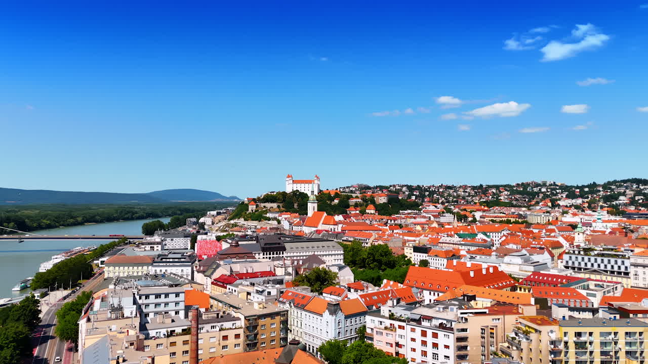 Flying over the gorgeous historical buildings in the old city of Bratislava, Slovakia. View on the river Danube and Tatra mountains at backdrop. Aerial view.