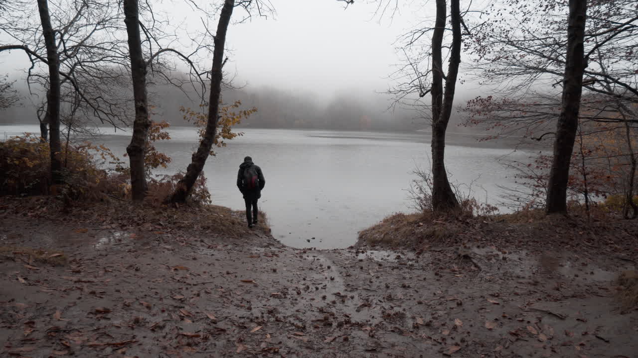 chico caminando por el hermoso bosque de hayas de otoño bajo la lluvia en las montañas catalanas