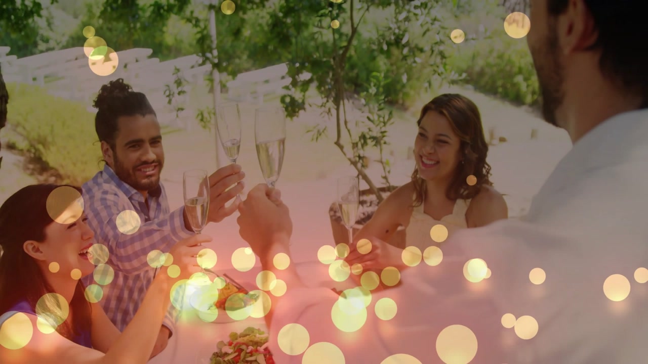Man leading toast at garden event friends raising flutes while gold bokeh rising over flutes