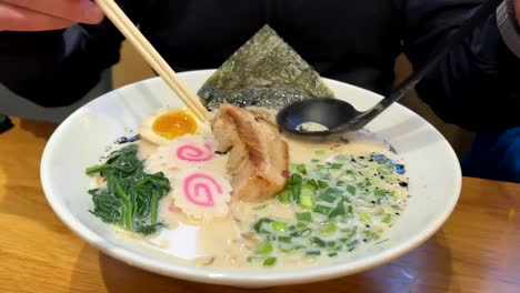 customer eating a bowl of japanese ramen using chopsticks