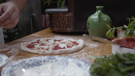 chef tops neapolitan pizza with mozzarella cheese