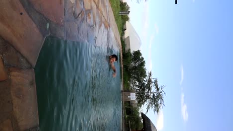 toma vertical de un hombre nadando en una piscina con el volcán ol doinyo lengai detrás