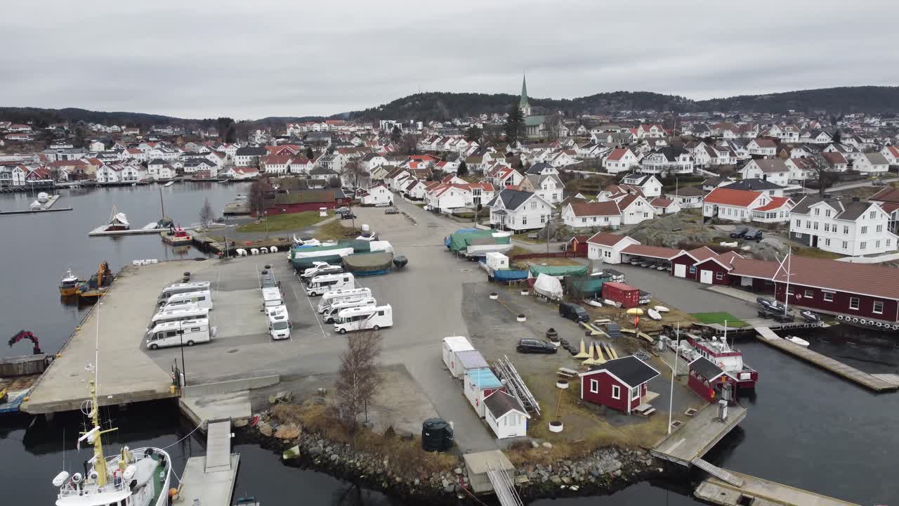 Lillesand, Norwegen – Aufsteigende Luftaufnahme vom Yachthafen und der Uferpromenade bis zur Gesamtübersicht der Stadt an einem bewölkten Morgen.
