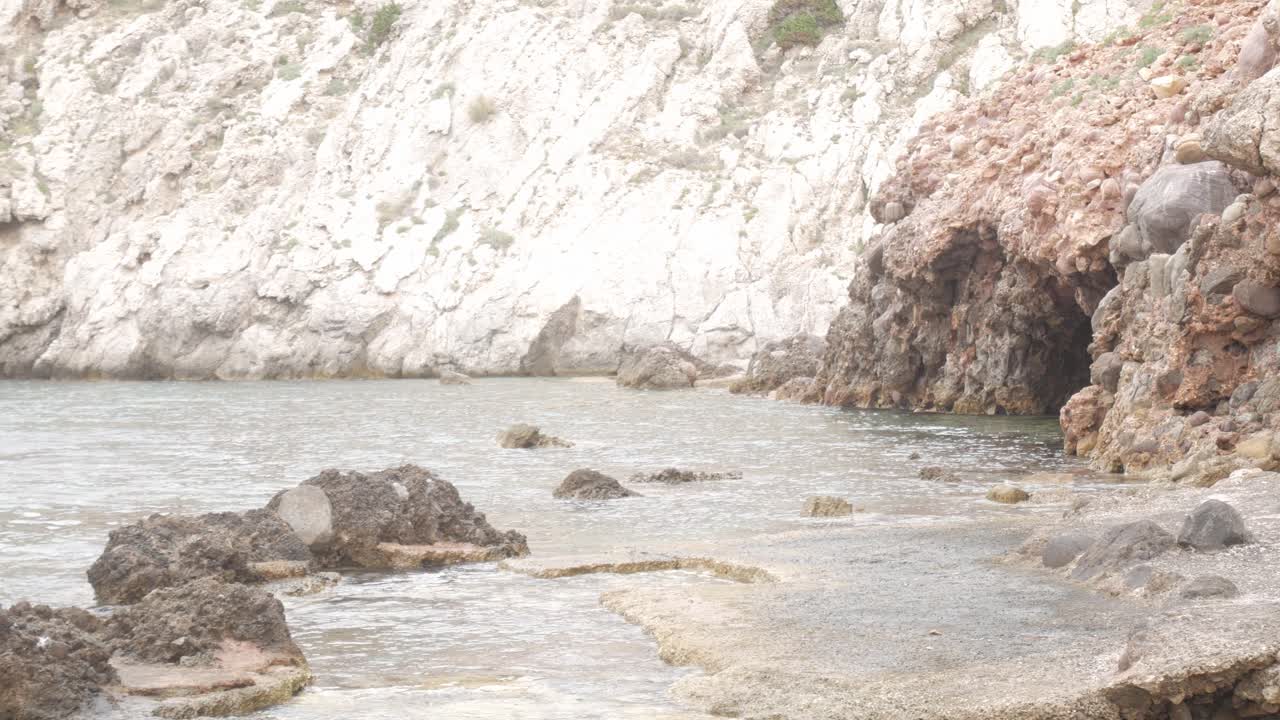 Rocky coastal cave at Cala Morell, Menorca, with textured cliffs and calm waters