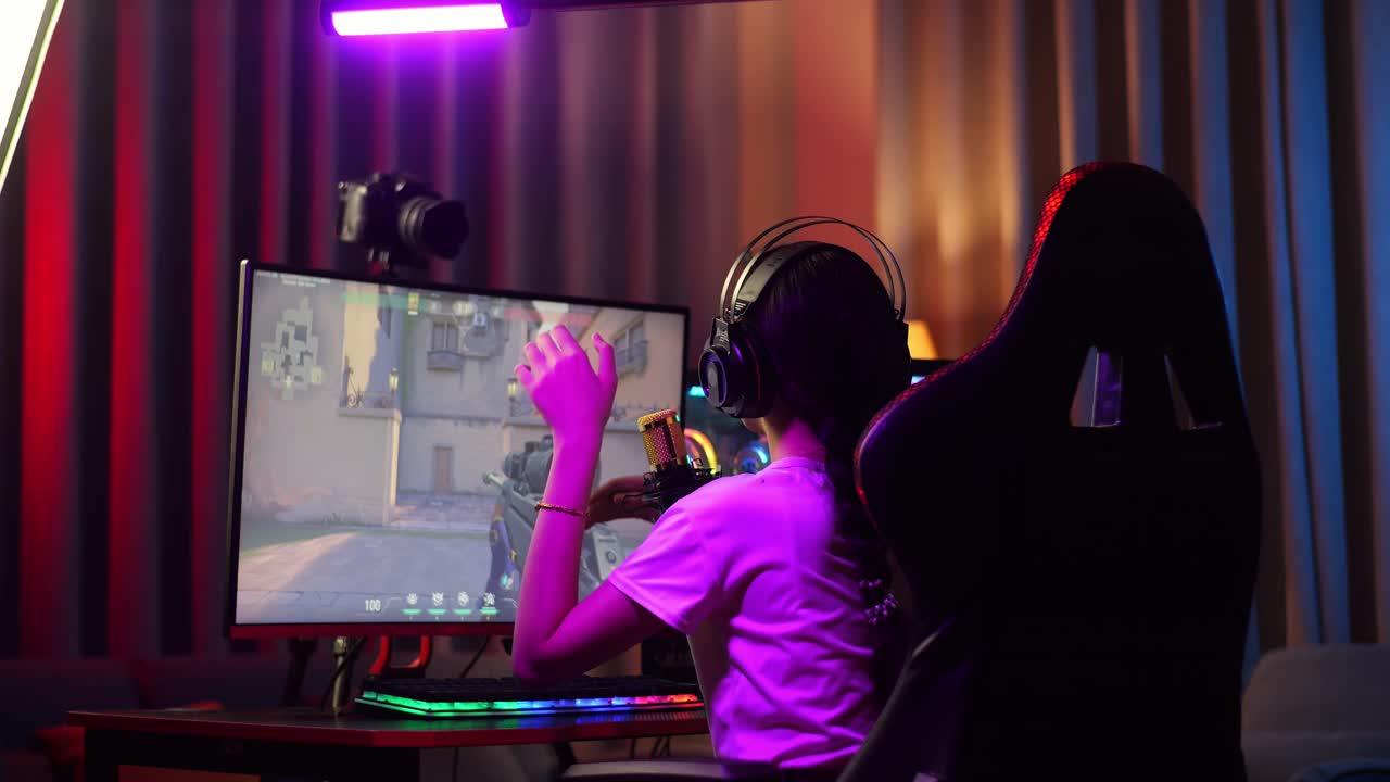 Back View Of Asian Girl Streamer Playing Game Over Network On Personal Computer. Live Stream Video Game, Desk Illuminated By Rgb Led Strip Light