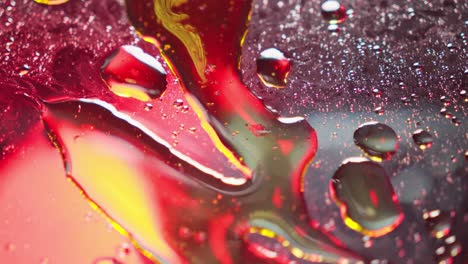 la luz pasa sobre el patrón líquido húmedo de aceite de miel roja que brilla en la superficie reflectante