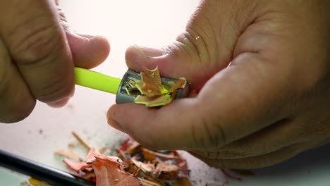 footage of hands slowly sharpening a pencil and some coloured pencils with a wedge pencil sharpener