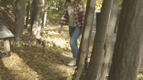 handheld shot of a young woman crossing a street in some trees