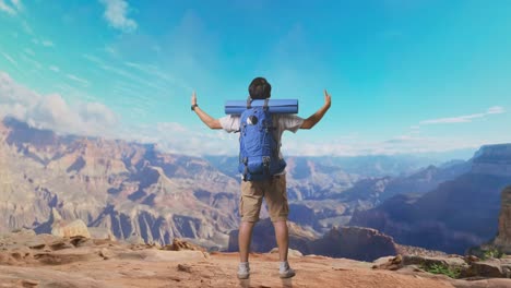 full body back view of a male hiker with mountaineering backpack spreading arms and looking the view around while traveling at the top of mountain