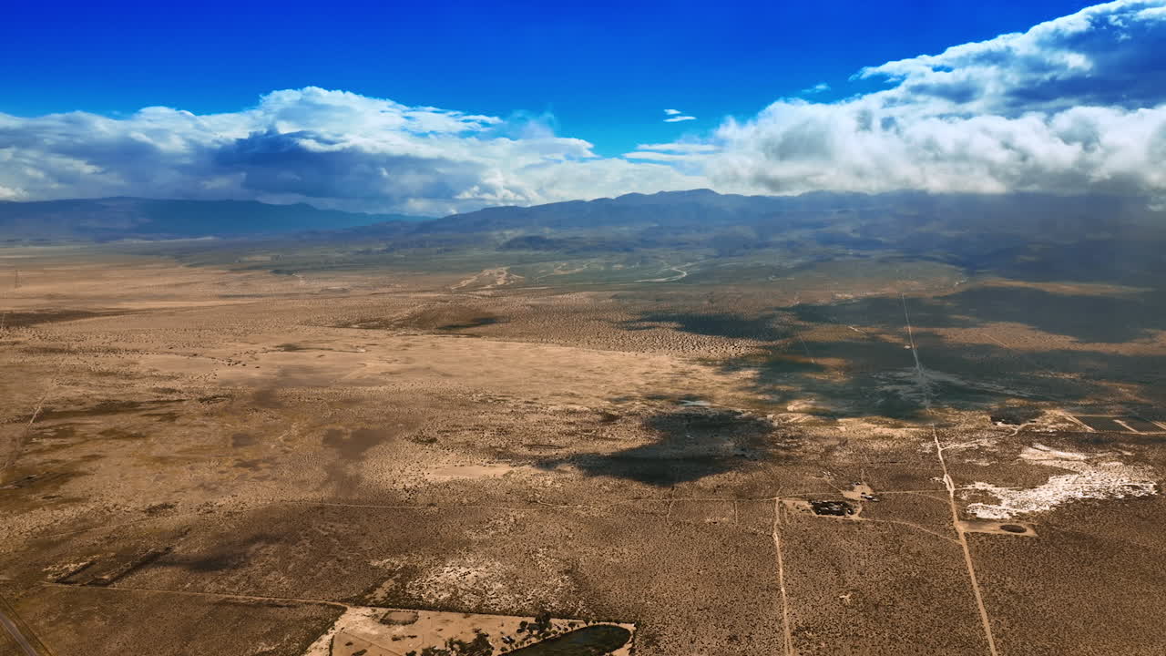 White cloudscape slowly floating in the air covering the desert from sun. Arid scenery of Death Valley from top view.