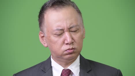 mature japanese businessman looking tired and bored