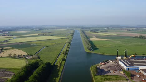 Aerial-shot-of-the-Canal-through-Walcheren-and-industry-in-Zeeland,-the-Netherlands,-on-a-sunny-summer-day