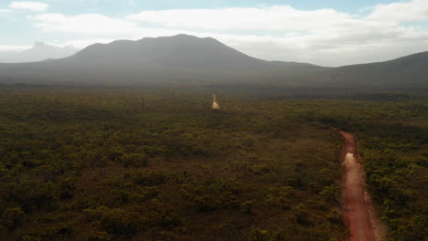 Aerial,-drone-shot-overlooking-a-four-wheel-drive-car,-on-a-red-sand,-desert-road,-sunny-day,-in-Hassell-National-Park,-West-Australia